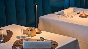 A dining table set with cutlery, a glass, a napkin, and a candle holder.