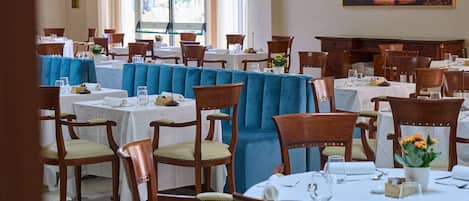 Un restaurant avec plusieurs tables, des chaises et une grande fenêtre.