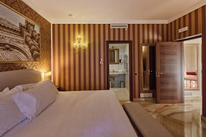 Una habitación de hotel con una cama grande, un baño con espejo y una puerta que da a otra habitación.