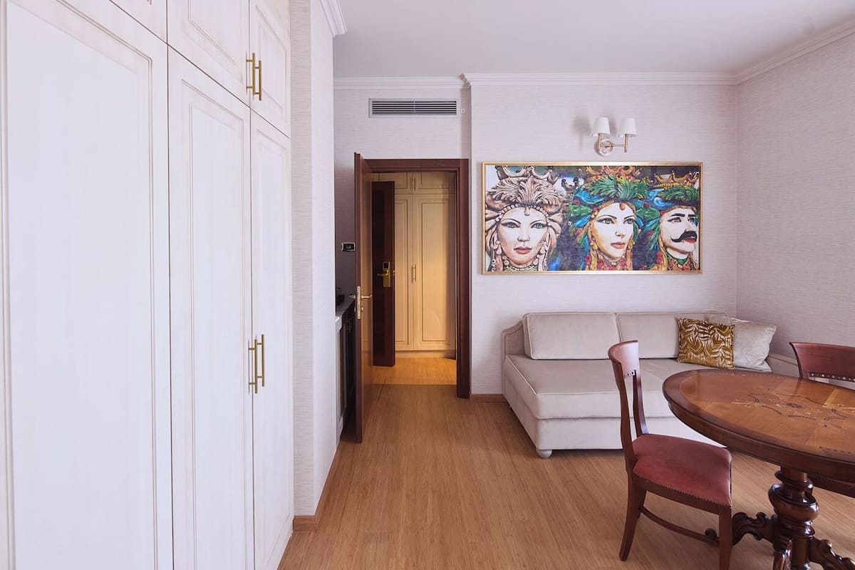 A room with a dining table, a sofa, and a painting on the wall.