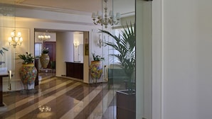 A hotel lobby with a check-in desk, a reception area, and a large mirror reflecting the interior.