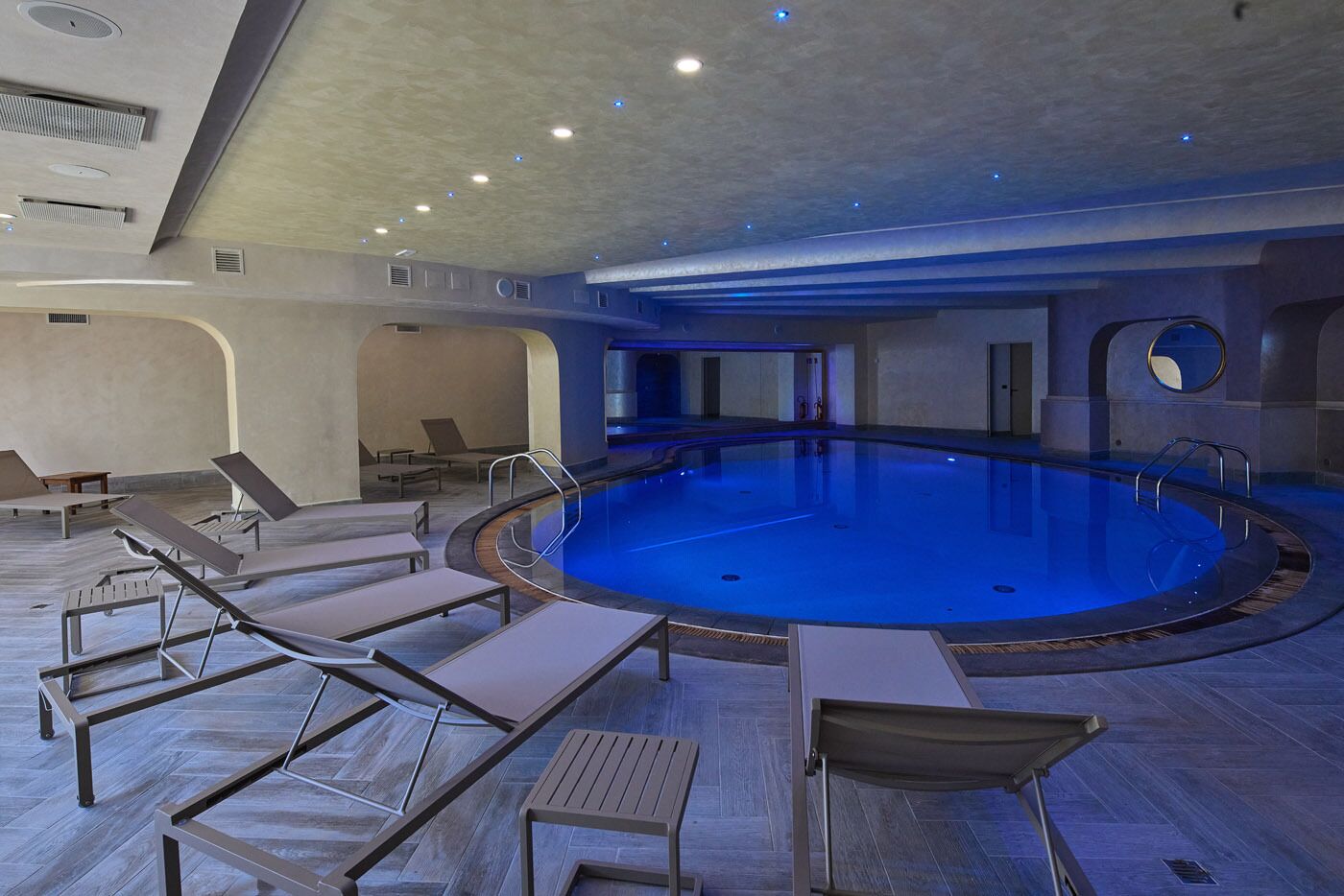 Une grande piscine intérieure dotée de chaises longues et d’un espace sauna.