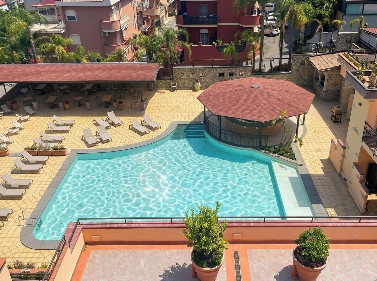 Une piscine sur le toit, dotée de chaises longues, d’un espace salon couvert et de plantes en pot.