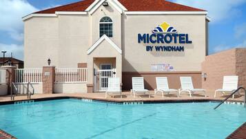 A swimming pool area with lounge chairs and a building labeled "MICROHOTEL BY WYNDHAM".