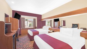 Une chambre d’hôtel avec deux lits, un bureau, une télévision et une fenêtre donnant sur des immeubles.
