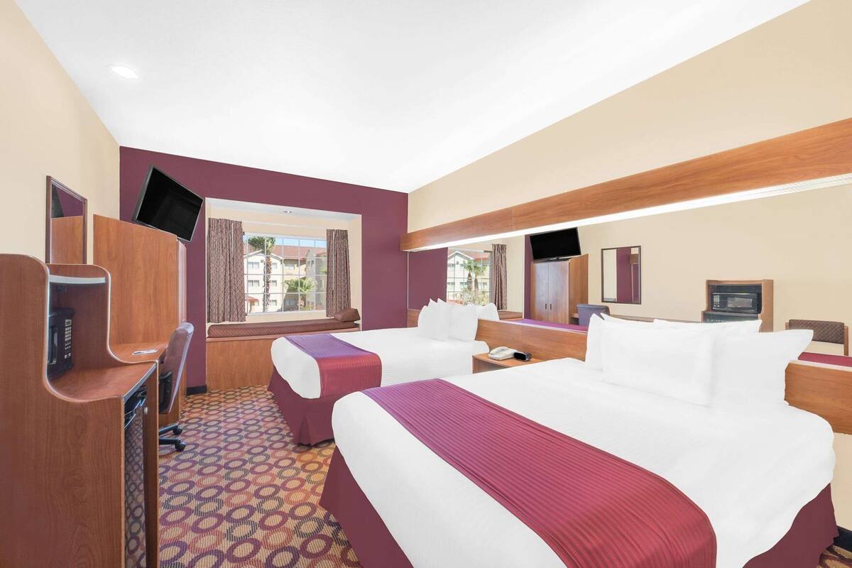 Een hotelkamer met twee bedden, een bureau, een televisie, een raam met uitzicht en een magnetron.
