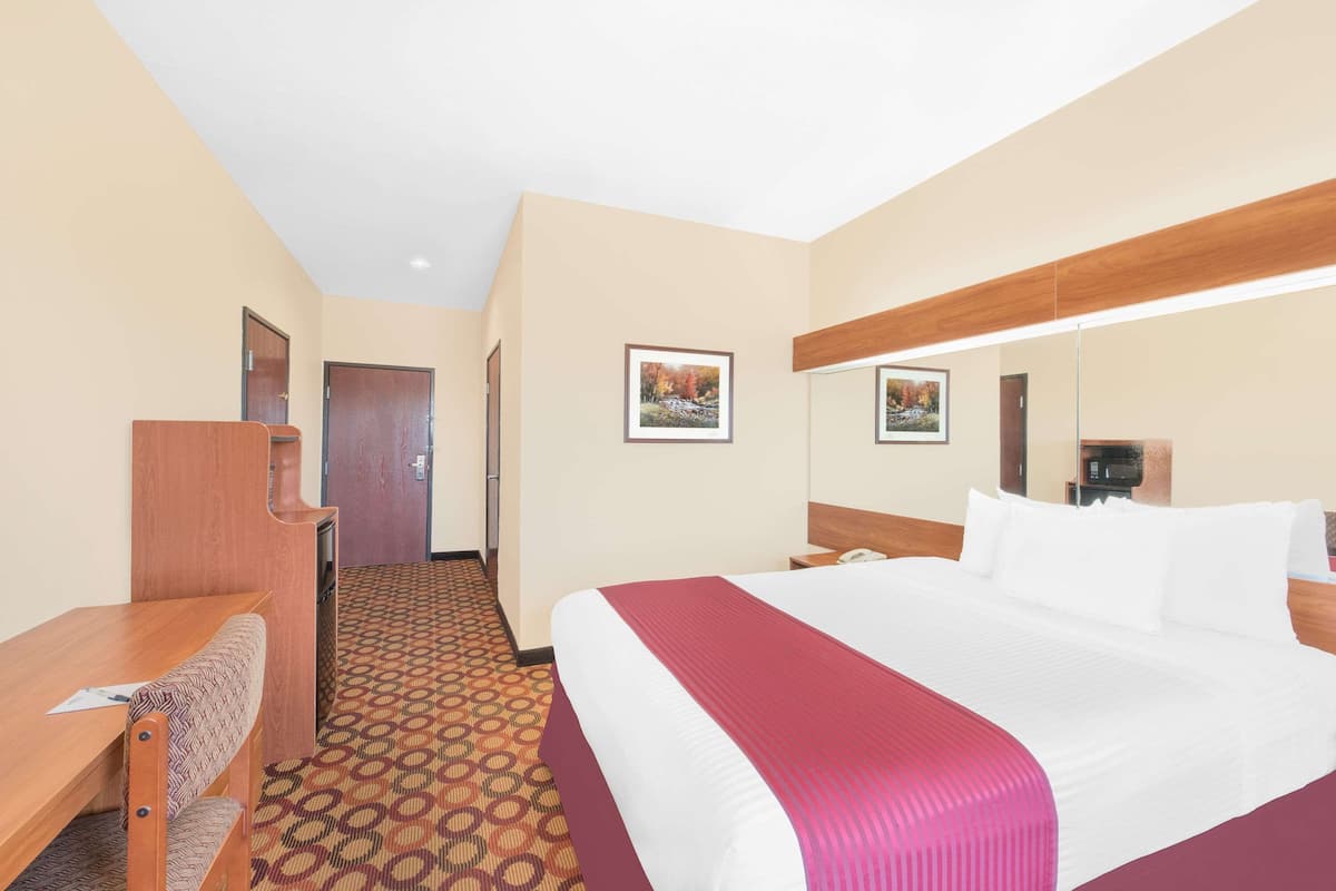 Een hotelkamer met een groot bed, een bureau, een stoel en een kamerbreed tapijt met een patroon.