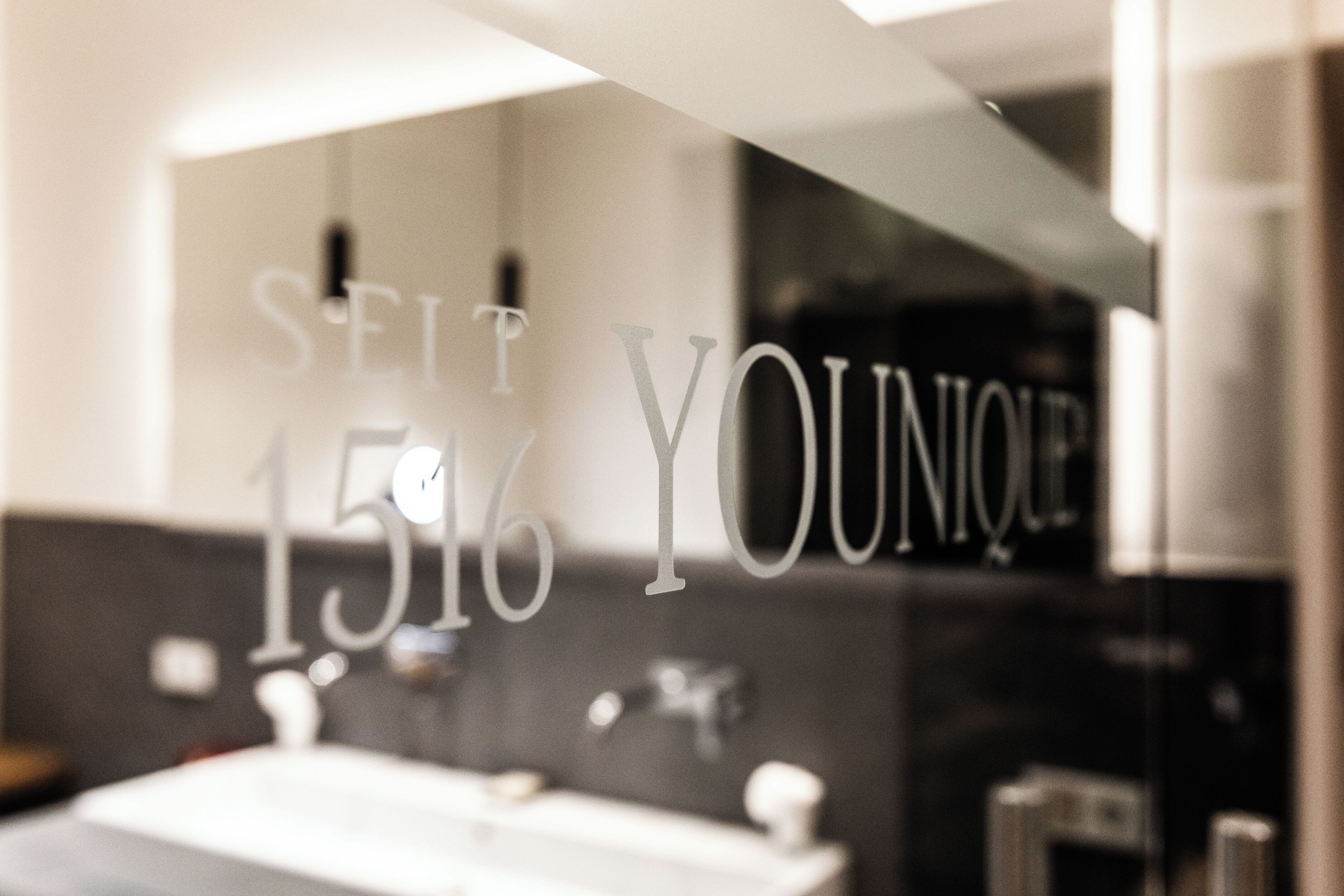 Ein Badezimmer mit einem Spiegel, der den Text "SEIT YOUNQUE 1516" reflektiert.