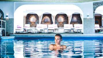 Una piscina cubierta, una piscina al aire libre, sombrillas, tumbonas