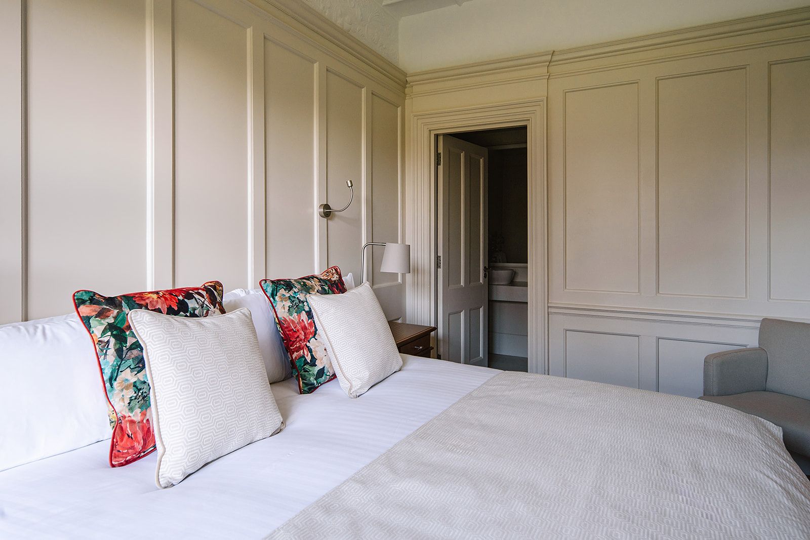 A hotel room with a large bed, a bedside table, a lamp, and a wardrobe.