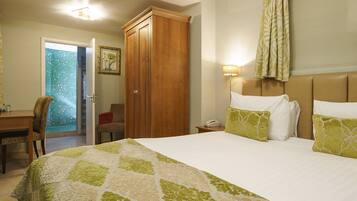 A hotel room with a bed, a desk, a chair, a wardrobe, and a bathroom with a shower.