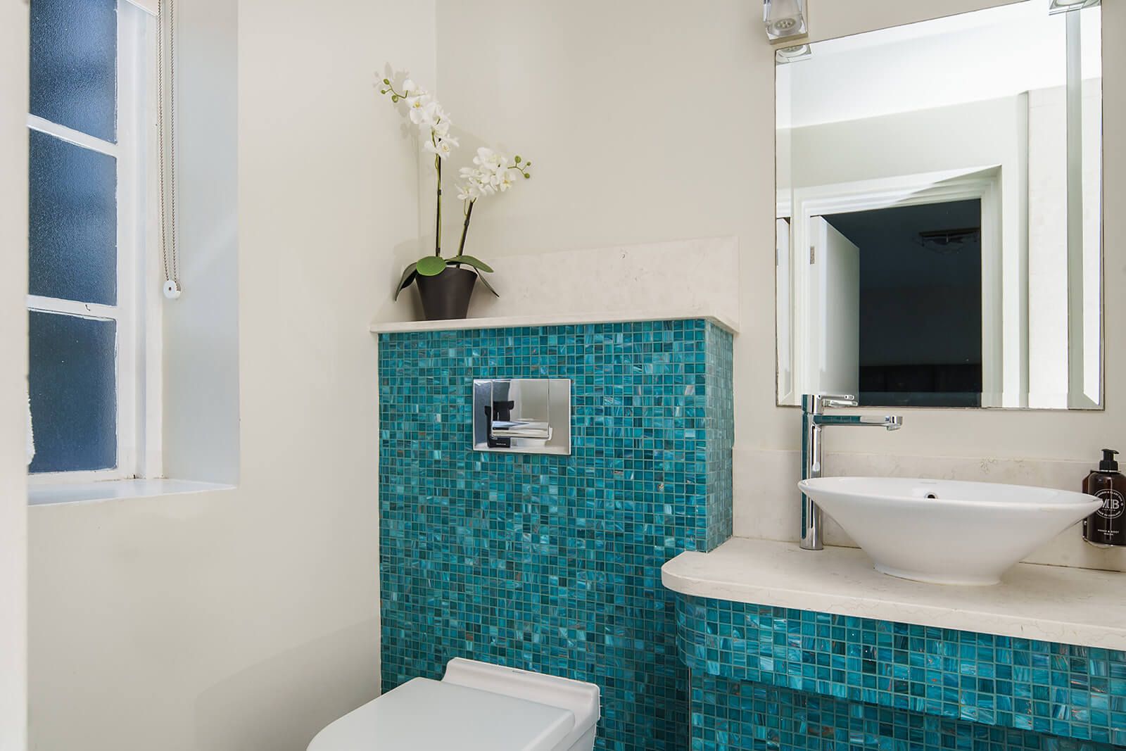 Un baño con lavamanos blanco, un espejo y un inodoro.