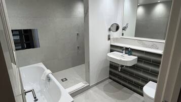 Ein modernes Badezimmer mit Badewanne, Dusche und Toilette.