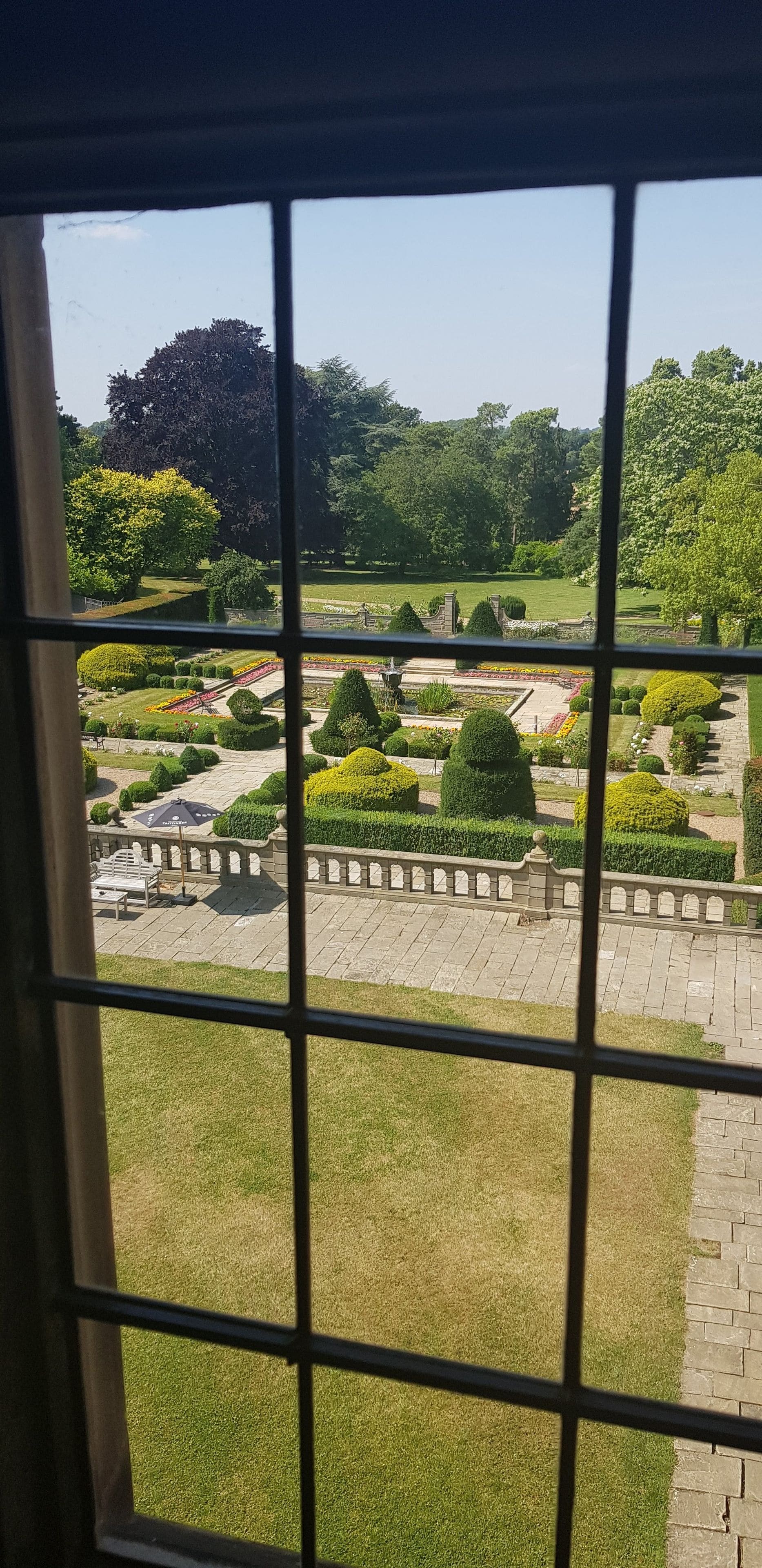 Vista de un jardín bien cuidado con césped impecable, setos y parterres de flores.