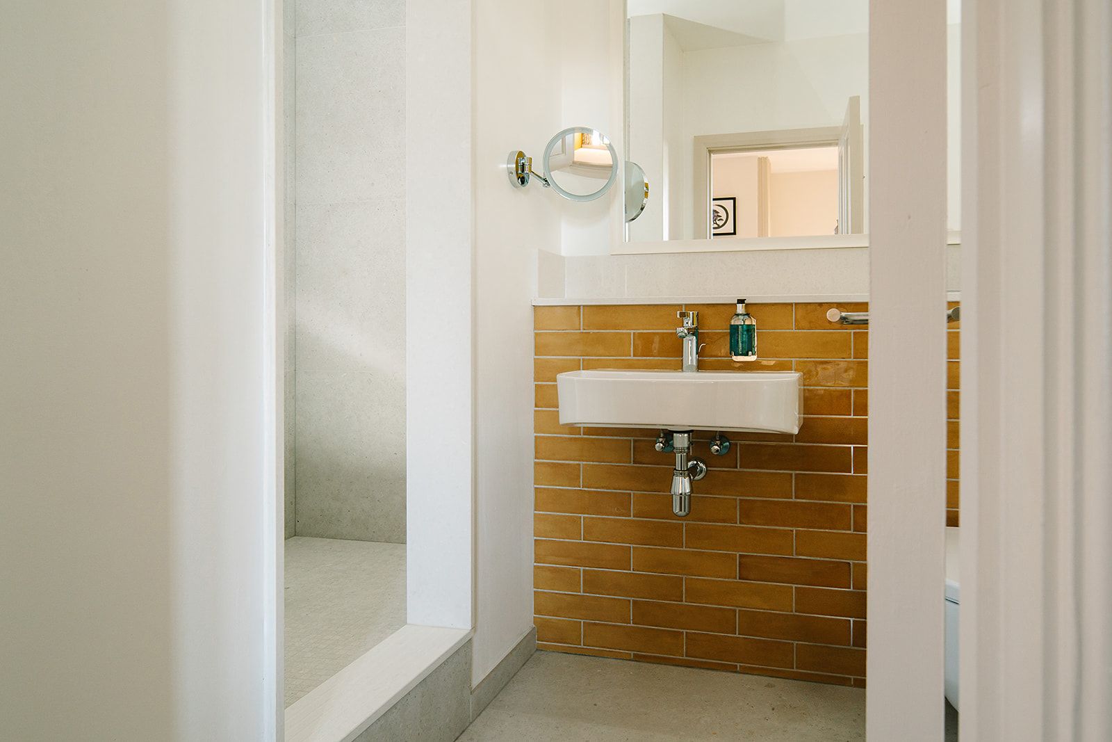 Une salle de bain avec un lavabo blanc, un miroir et un espace douche.