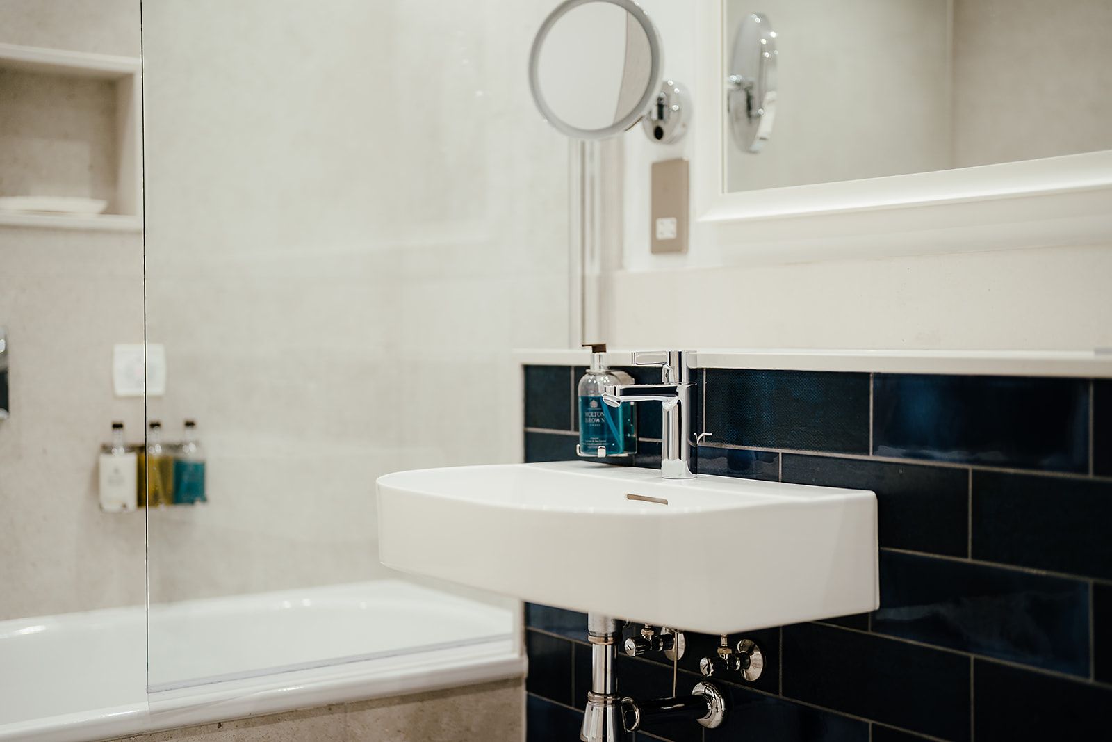 A bathroom with a white sink, a mirror, and a bathtub.
