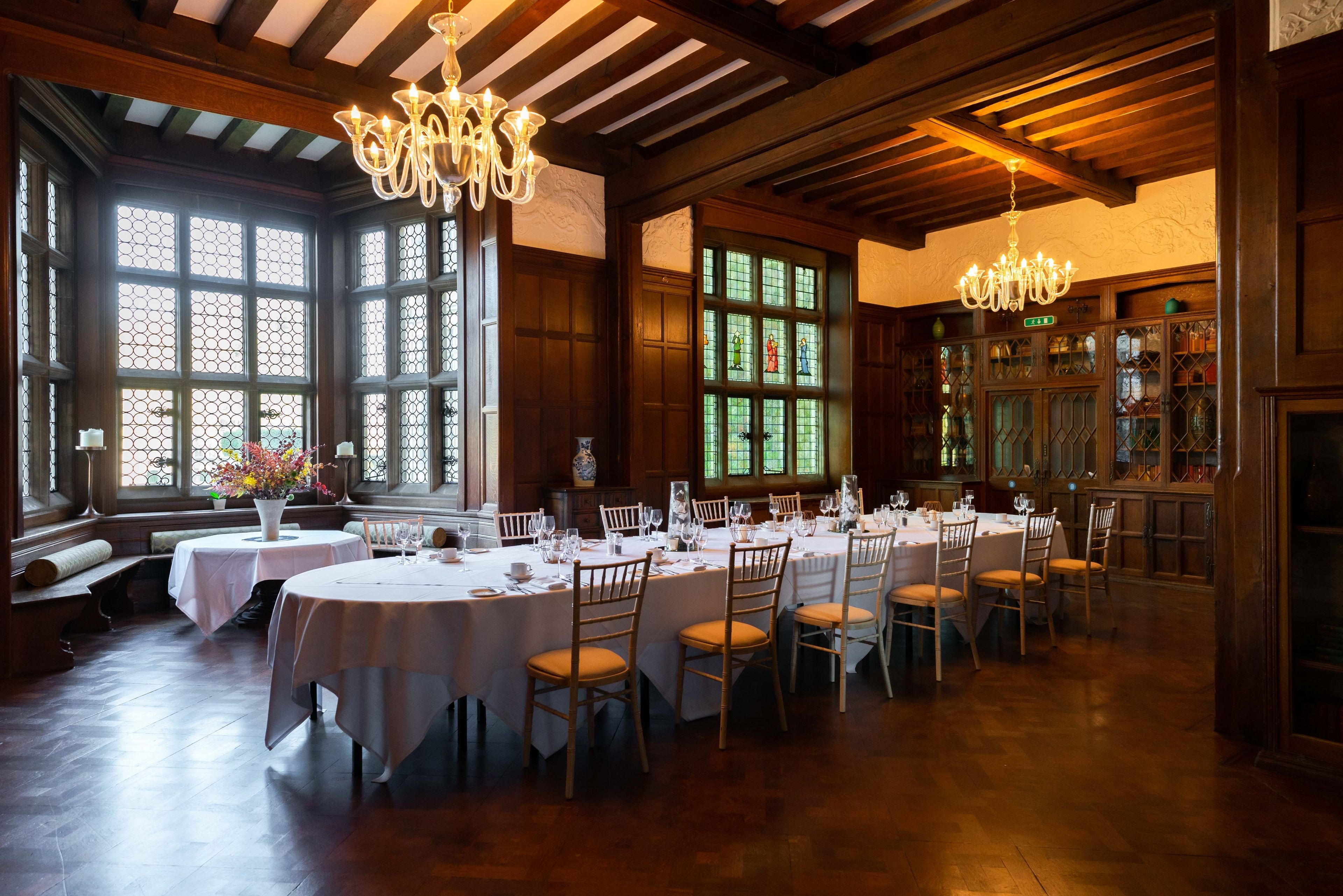A dining area with round tables, chairs, and chandeliers.