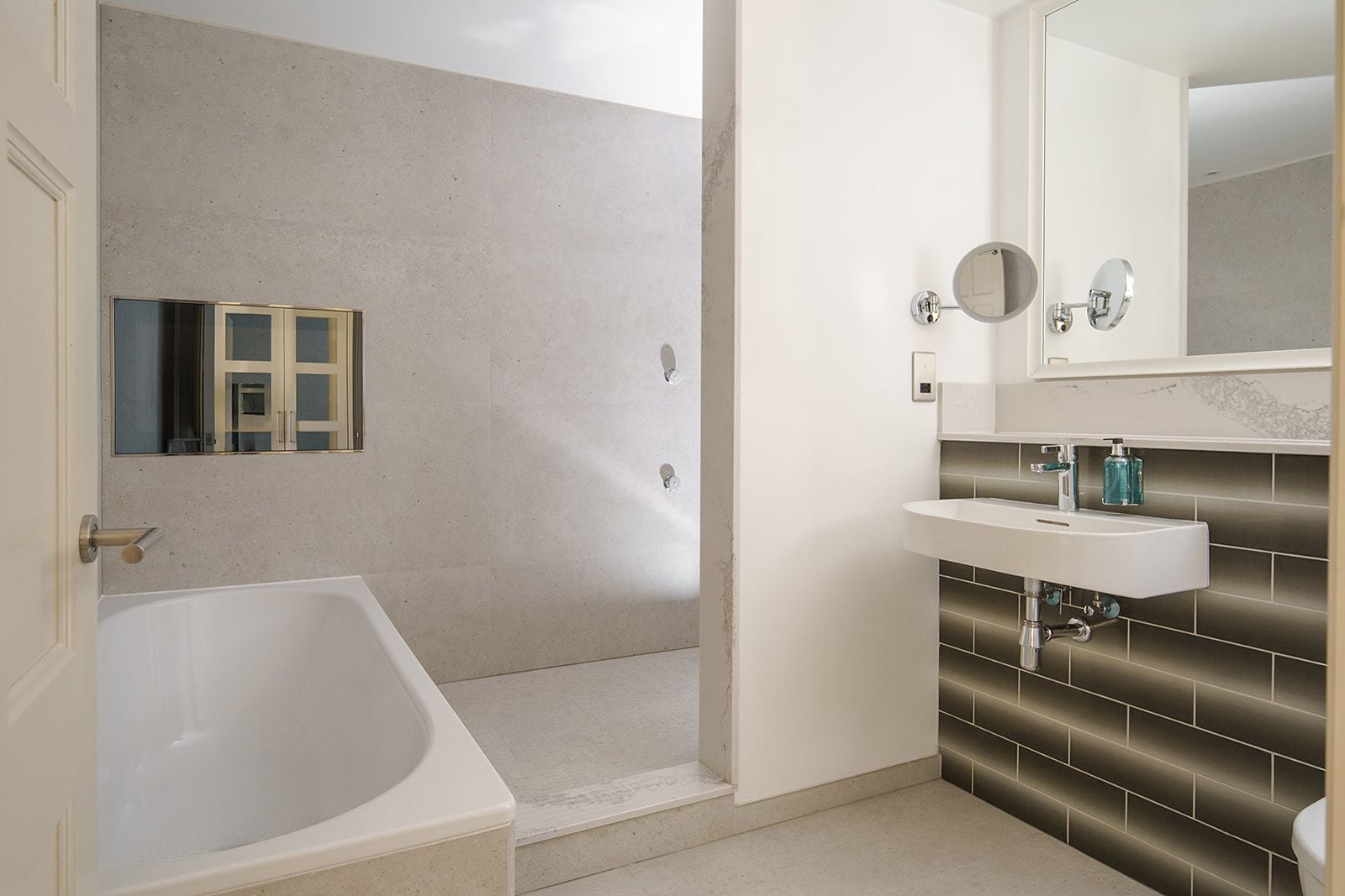 Un baño con bañera, lavabo con espejo y zona de ducha.