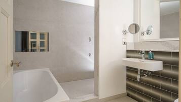 Un baño con bañera, lavabo con espejo y zona de ducha.
