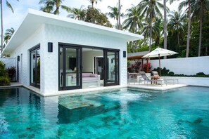 A modern house with a pool, large glass doors, and a patio with lounge chairs.