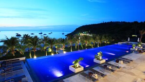 Zona junto a la piscina con sillones de descanso y vista al mar.