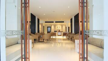 A modern hotel lobby with a reception desk, seating area, and a polished floor.