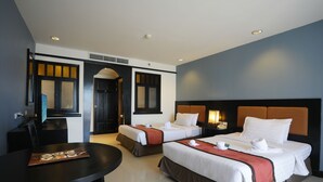 Habitación de hotel con dos camas, una mesa de comedor y un televisor.
