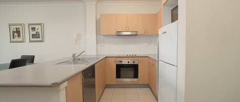 A modern kitchen with light wood cabinets, a stainless steel sink, and a built-in oven.