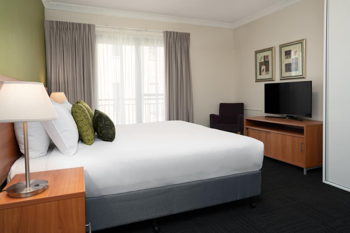 Una habitación de hotel con una cama grande, un escritorio con televisor y una silla.