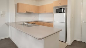 Una cocina moderna con armarios blancos, un refrigerador de acero inoxidable y un microondas integrado.