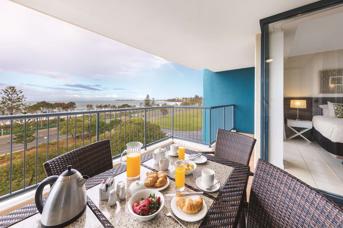 Un balcon aménagé pour le petit-déjeuner, avec des croissants, des fruits et du jus d’orange.