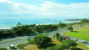 A coastal road with a view of the ocean and a distant city skyline.