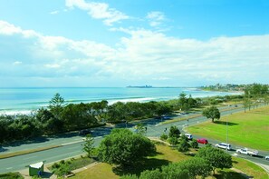 A coastal road with a view of the ocean and a distant city skyline.