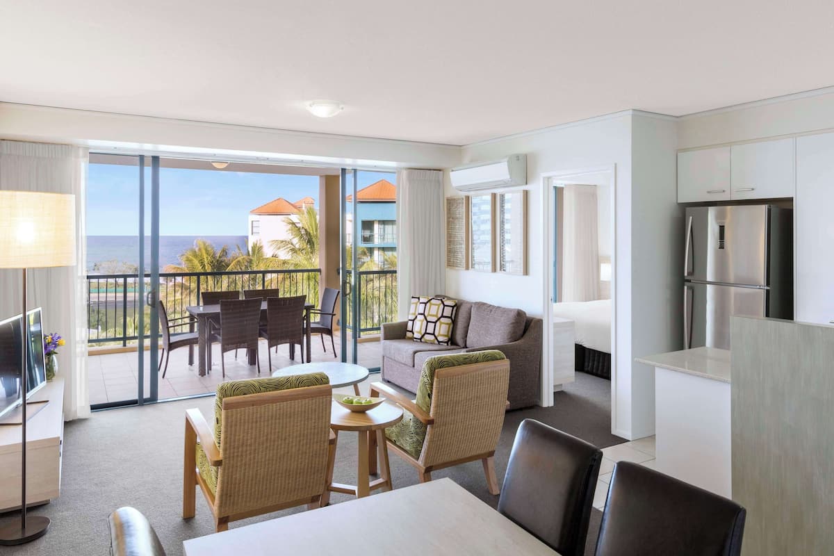 Une chambre d’hôtel avec un balcon, un coin repas, un canapé et une cuisine.