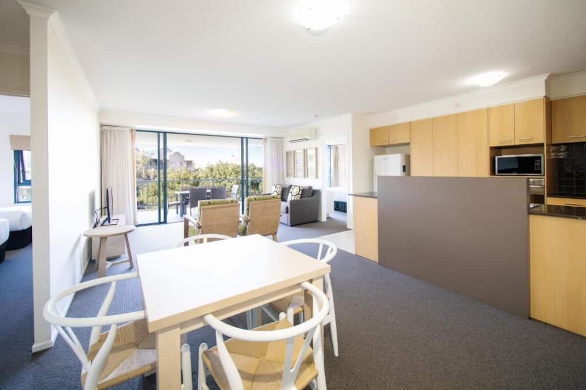Une chambre d’hôtel moderne dotée d’un coin repas, d’une cuisine et d’un balcon avec vue.