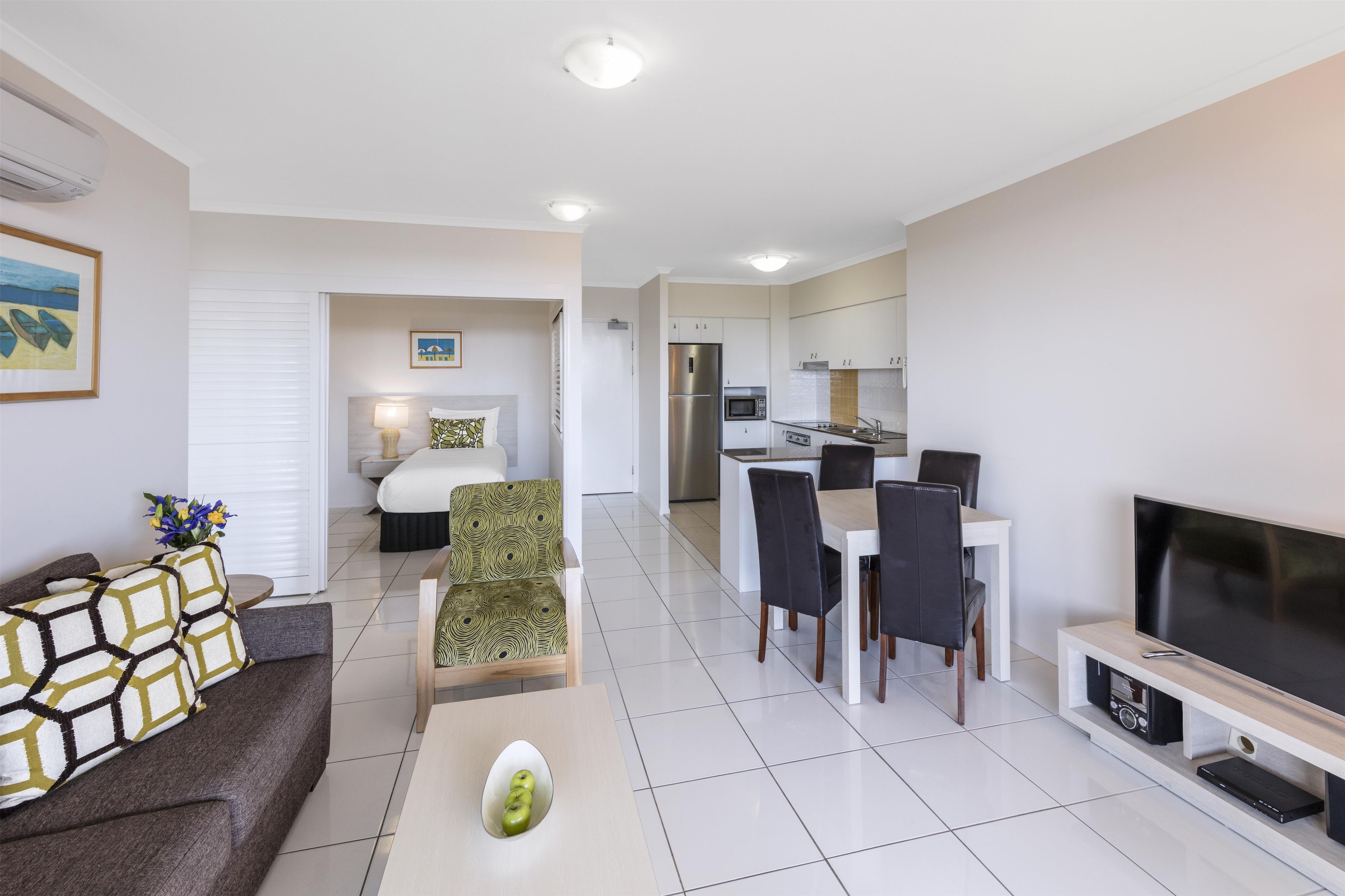 A modern apartment with a living room, dining area, kitchenette, and a bedroom.