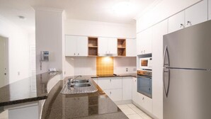 A kitchen with white cabinets, a granite countertop, a stainless steel refrigerator, and a built-in oven.