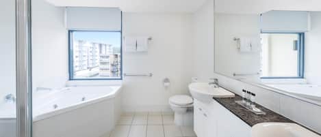 Un baño moderno con un ventanal grande, una bañera, un inodoro y un lavamanos.