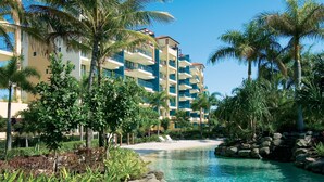 A resort with a pool, palm trees, and a beach area.