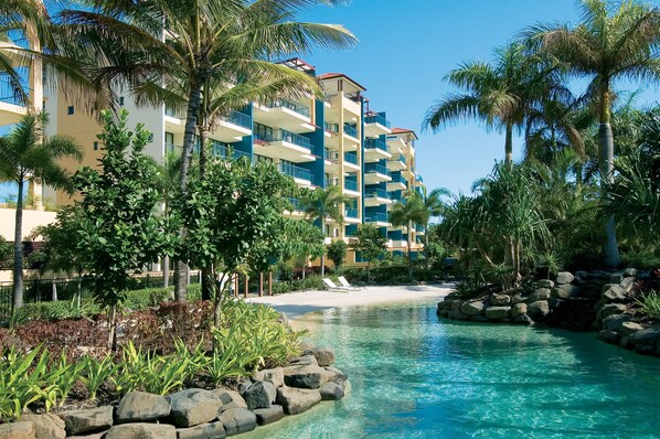 Et resort med pool, palmer og en badestrand.