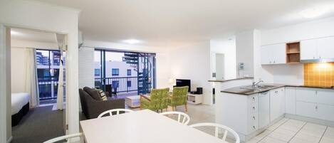 A modern apartment with a dining area, kitchen, and a balcony with a view.