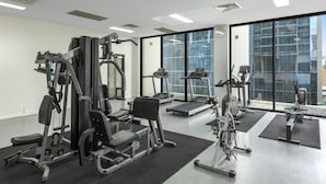 Een moderne sportschool met diverse trainingsapparaten, grote ramen en een ruimtelijk, schoon design.