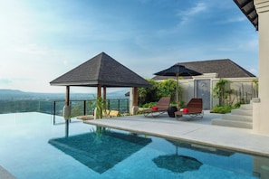 Ein moderner Infinity-Pool mit freiem Blick auf die Landschaft, einem überdachten Sitzbereich und einem kleinen Pavillon.