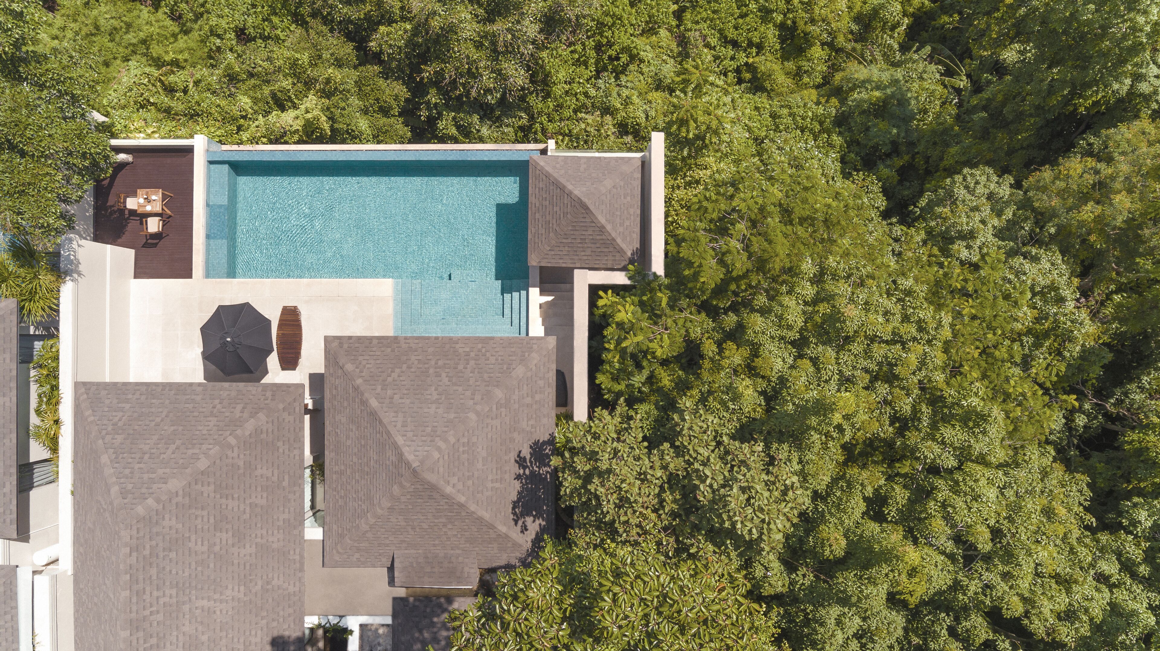 Vue aérienne d’une maison moderne dotée d’une piscine, entourée d’une végétation luxuriante.