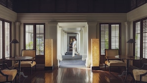 A hotel lobby with a wooden floor, a central staircase, and seating areas with tables and chairs. - The Pavilions Phuket (Choeng Thale)