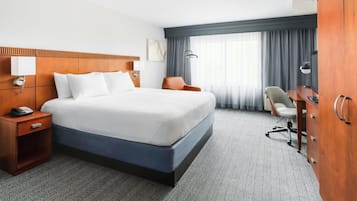 Una habitación de hotel con una cama grande, un escritorio, una silla y un armario.