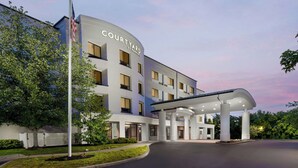 A Courtyard hotel with a covered outdoor area and a flagpole. - Courtyard By Marriott Farmington (Newington)