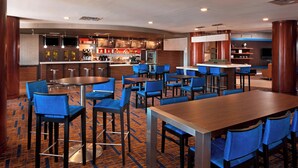 A hotel lobby with a bar area, multiple seating arrangements, and a patterned carpet. - Courtyard By Marriott Farmington (Newington)