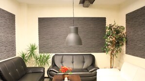 Una sala de estar moderna con un sofá de cuero negro, un sofá blanco, una mesa de centro de madera con un jarrón de flores y una lámpara colgante.