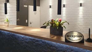 Un mostrador de recepción con un cartel que dice "RECEPTION Rheingoldhotel", plantas en macetas y lámparas colgantes.